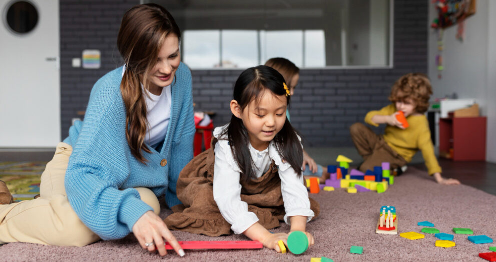child care educator helping girl learn